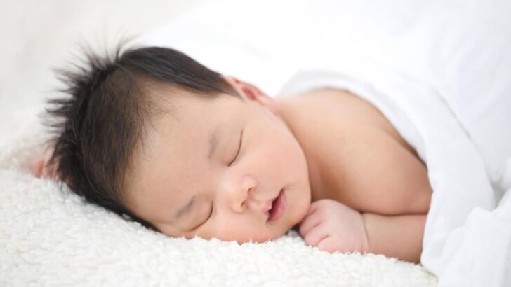 Bebê cabeludo dormindo com cobertor branco