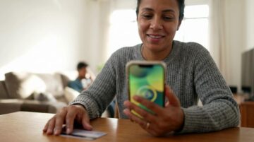 Pessoa brasileira em casa conferindo PIS pelo CPF no celular com expressão de alívio, tela do aparelho desfocada e sem textos legíveis