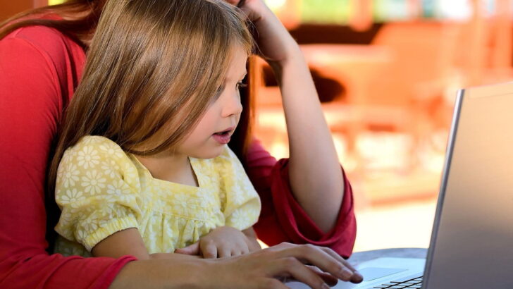 mulher trabalhando no computador com a filha no colo