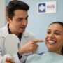 Paciente brasileiro sorrindo após receber implante dentário gratuito pelo SUS com dentista ao lado em clínica pública