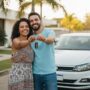 Casal brasileiro sorrindo ao lado de um Volkswagen Polo segurando a chave após conseguir comprar sem entrada e sem burocracia