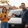 Pessoa brasileira sorrindo ao lado de uma Fiat Strada nova segurando chaves e um celular, representando compra sem entrada